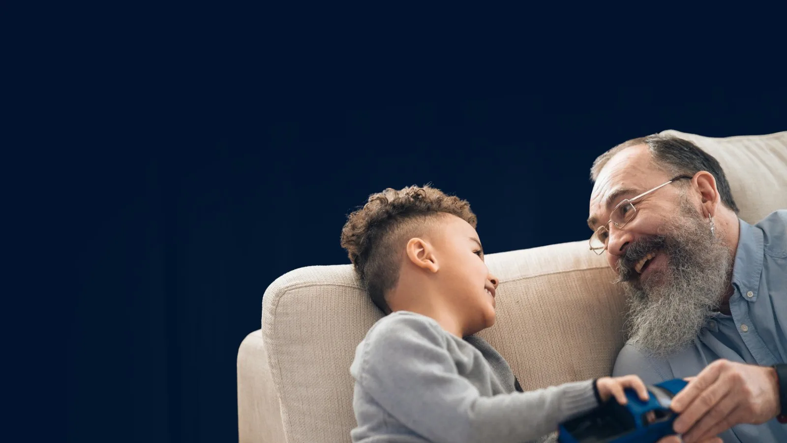 Grand-père et petit-fils jouant ensemble sur un canapé